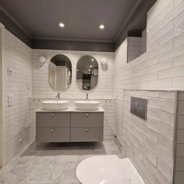 Modernt badrum med dubbla handfat och ovalt spegelpar