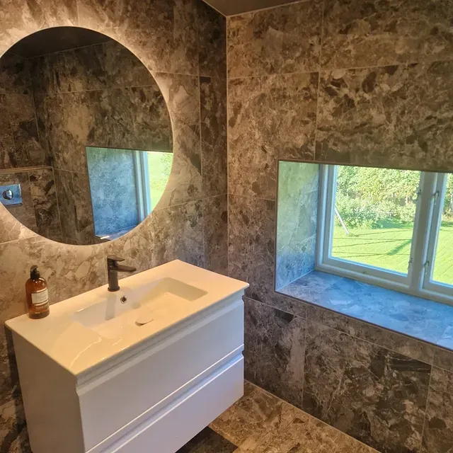 Exklusivt badrum med marmor och rund belyst spegel